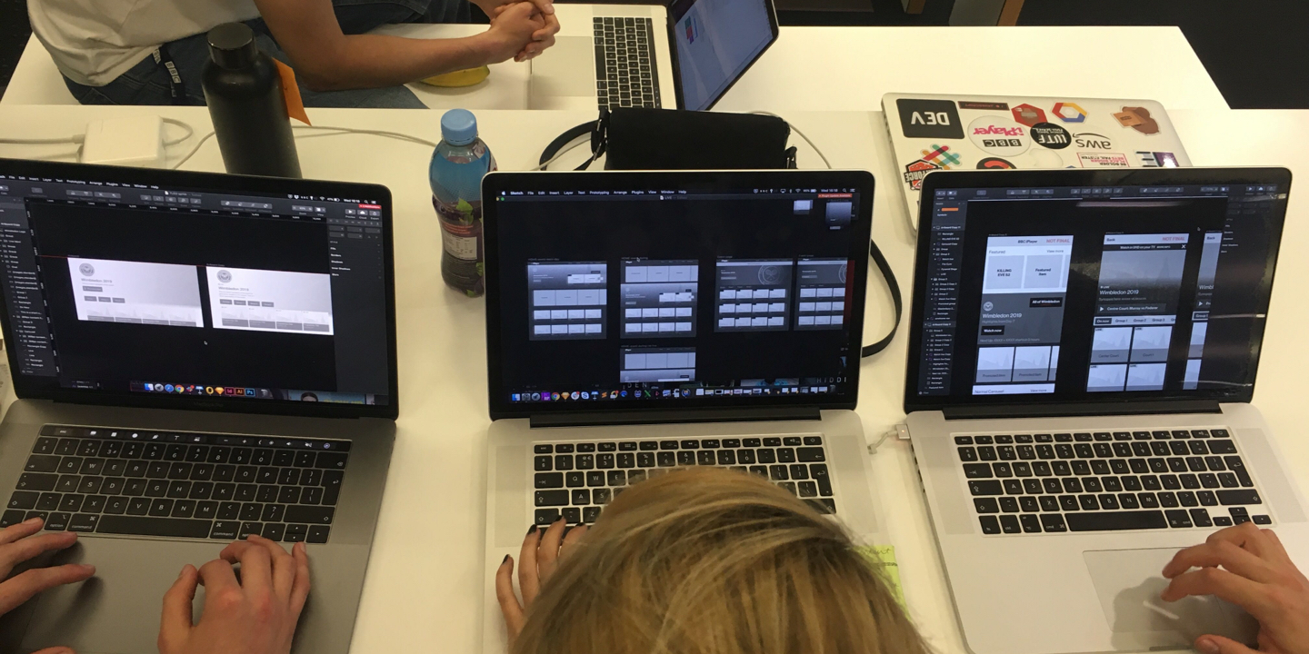 Four designers eagerly working through the wireframes depicting the outcome of the design sprint